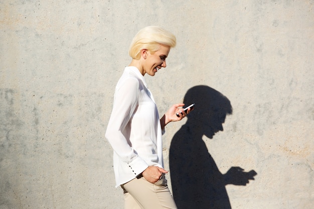 Femme souriante, lecture de SMS sur téléphone mobile