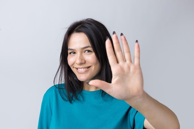 Une femme souriante leva la paume de la main vers le haut et vers l'avant comme un signe de la main.