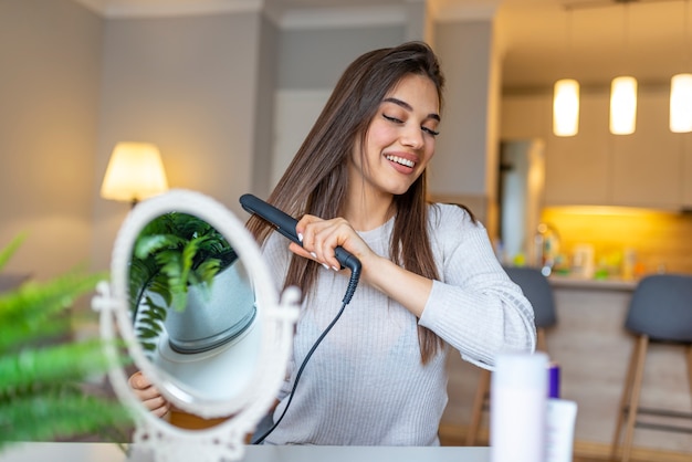 Photo femme souriante, lissant les cheveux devant le miroir.