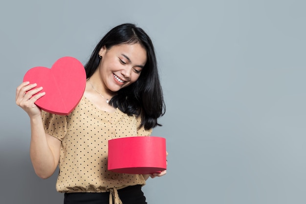 Femme souriante lors de l'ouverture d'une boîte-cadeau en forme de coeur