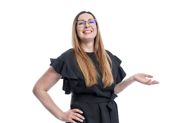 Femme souriante avec des lunettes Une belle brune dans un chemisier noir tient sa main paume vers le haut Succès optimisme et positivité Isolé sur fond blanc