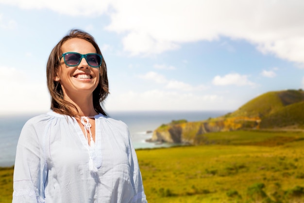 Une femme souriante avec des lunettes de soleil sur la côte de Big Sur.