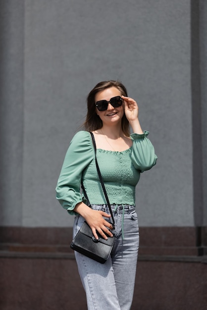 Une femme souriante à lunettes de soleil regarde la caméra