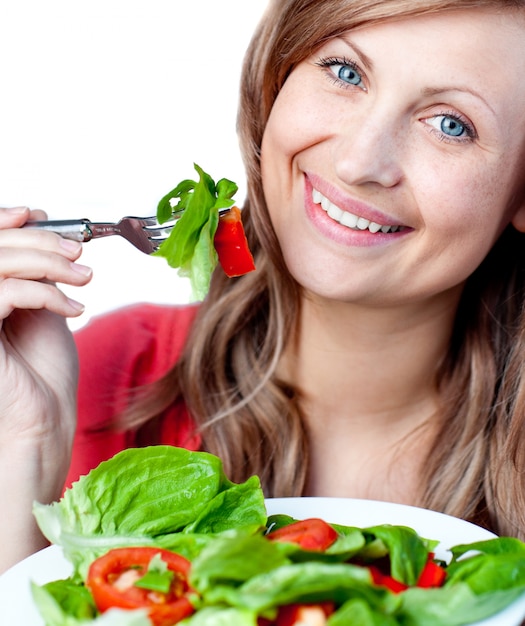 Femme souriante mange une salade