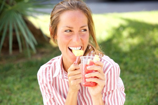 Une femme souriante mangeant des fruits dans un parc