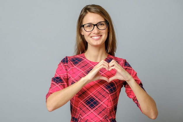 Femme souriante, montrant le cœur à deux mains, signe d'amour