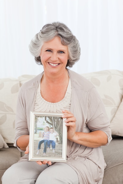 Femme souriante montrant une photo de son petit-enfant