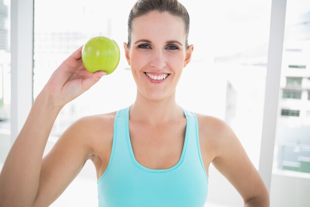 Femme souriante, montrant une pomme verte