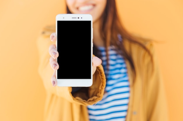 Photo femme souriante montrant un téléphone intelligent écran blanc sur fond jaune