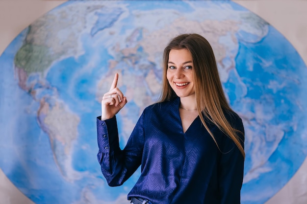 Une femme souriante montre le point de la carte internationale avec son doigt ayant une excellente idée