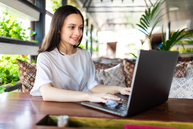 Femme souriante naviguant sur internet au café