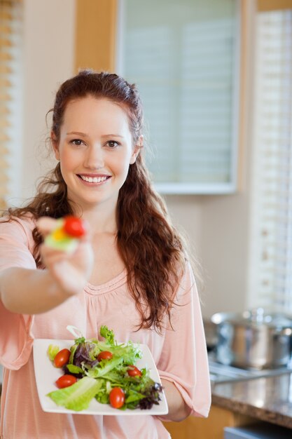 Femme souriante offrant une salade