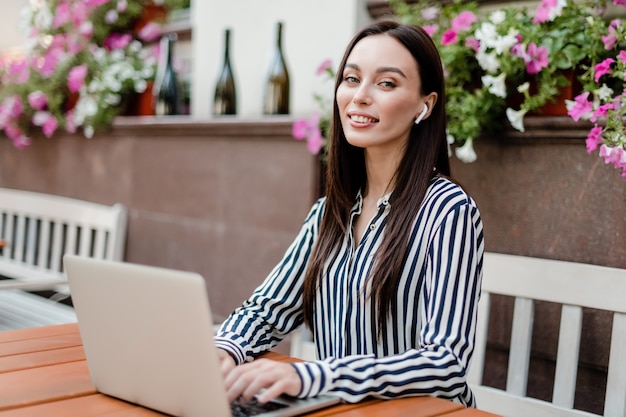 Femme souriante avec ordinateur portable assis au restaurant