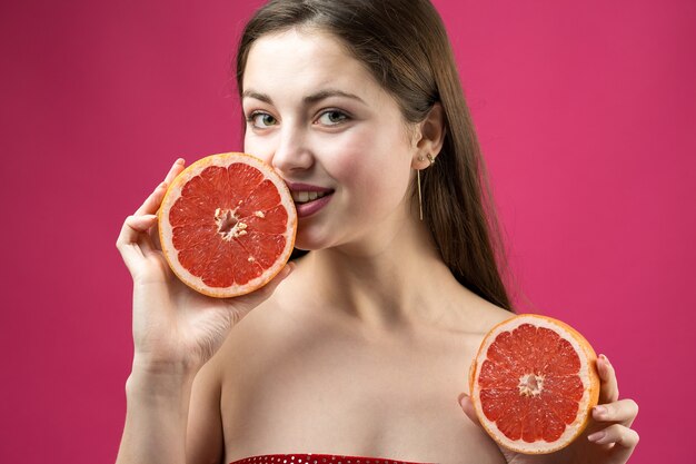 Femme souriante avec pamplemousse coupé en deux fruits à la main