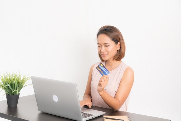 Femme souriante parcourant son ordinateur portable et sa carte de crédit.