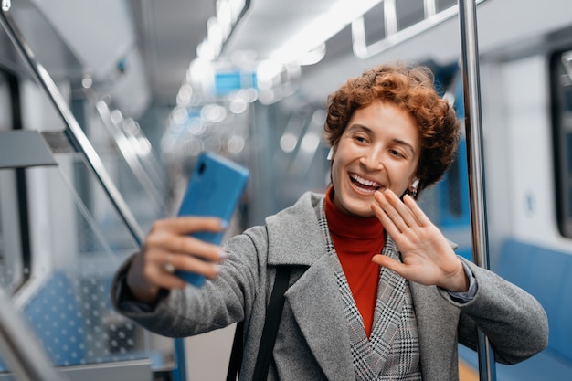 Femme souriante parlant sur une liaison vidéo dans une voiture de métro