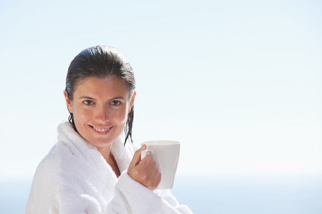 Femme souriante en peignoir avec une tasse de café