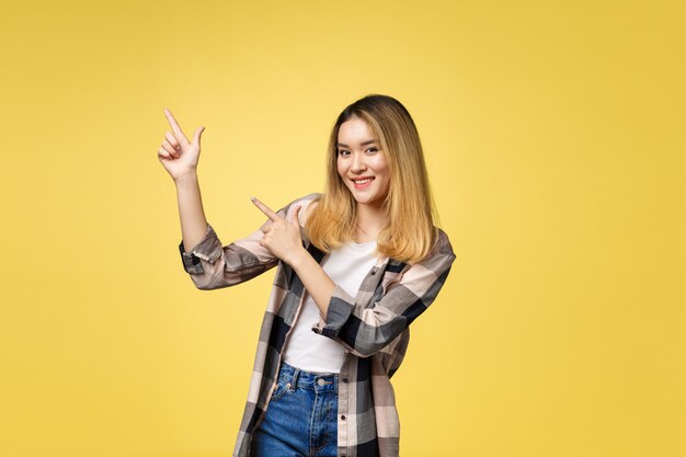 Femme souriante, pointant le doigt Portrait isolé sur jaune.