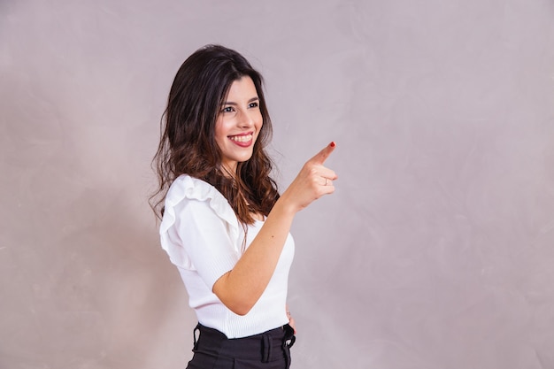 Femme souriante pointant son doigt en diagonale avec un espace libre pour le texte.