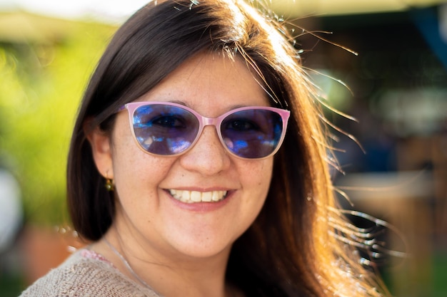 Femme souriante portant des lunettes debout et regardant la caméra