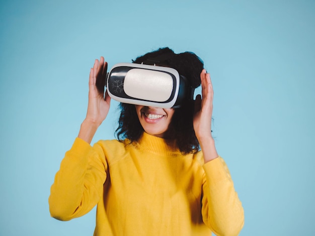 Une femme souriante portant des lunettes VR sur un fond bleu