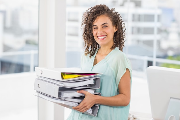 Femme souriante portant une pile de dossiers