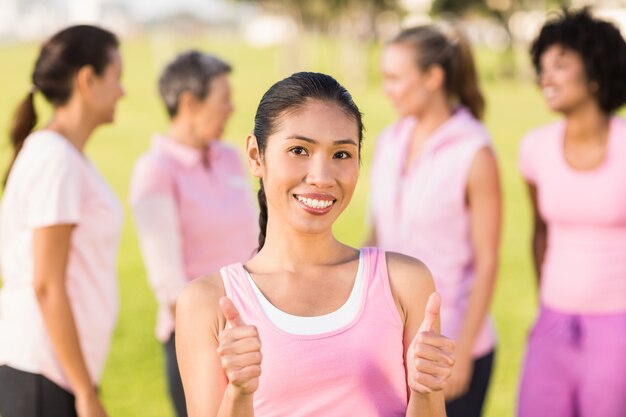 Femme souriante portant rose pour le cancer du sein devant des amis