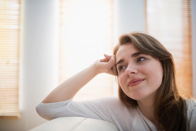 Femme souriante posant sur le canapé dans le salon