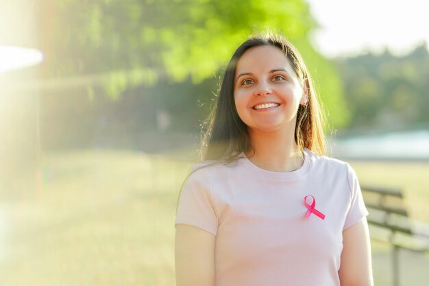 Photo femme souriante posant avec un ruban rose dans la rue concept du mois de sensibilisation au cancer du sein