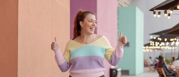 Photo femme souriante avec les pouces vers le haut fond pastelcolored