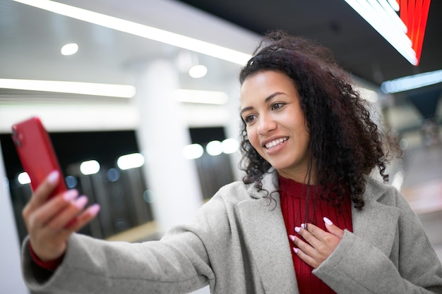 Femme souriante prenant un selfie debout sur un quai de métro