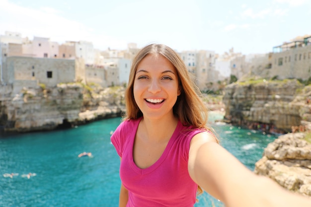 Femme souriante prendre selfie à Polignano une jument, Mer Méditerranée, Italie