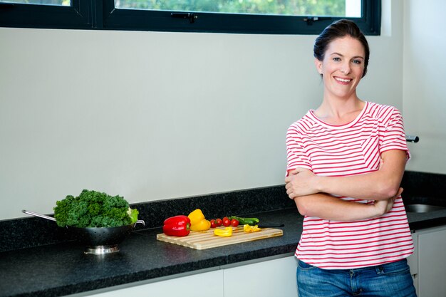 femme souriante prépare des légumes pour le dîner sur une planche à découper en bois