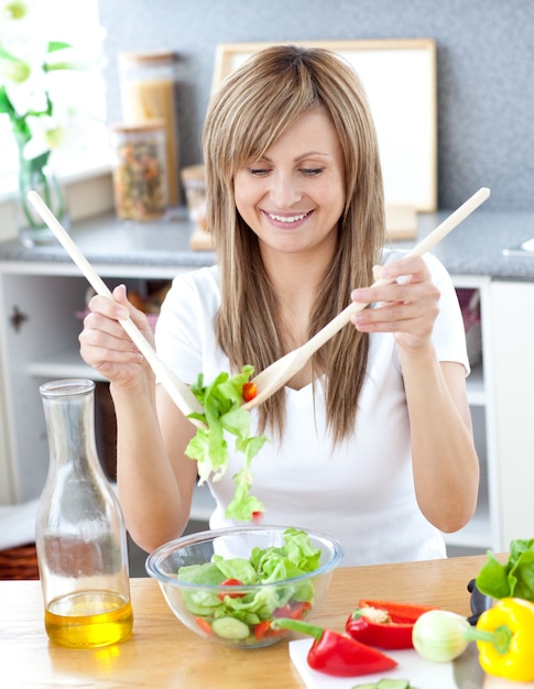 Femme souriante, préparer une salade dans la cuisine