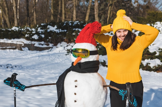 Femme souriante près de l'espace de copie de bonhomme de neige de skieur