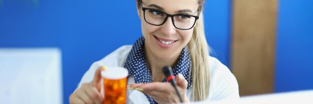 Femme souriante présentant des pilules en bouteille