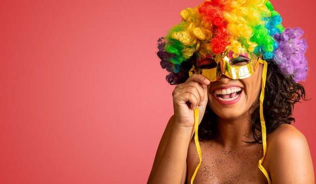 Femme souriante prête à profiter du carnaval avec une perruque et un masque colorés