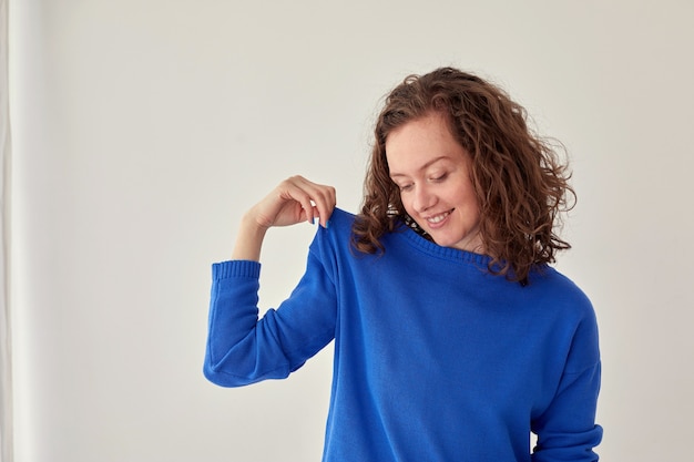 Femme souriante en pull bleu fond blanc