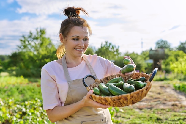 Photo femme souriante avec récolte de concombres à la ferme