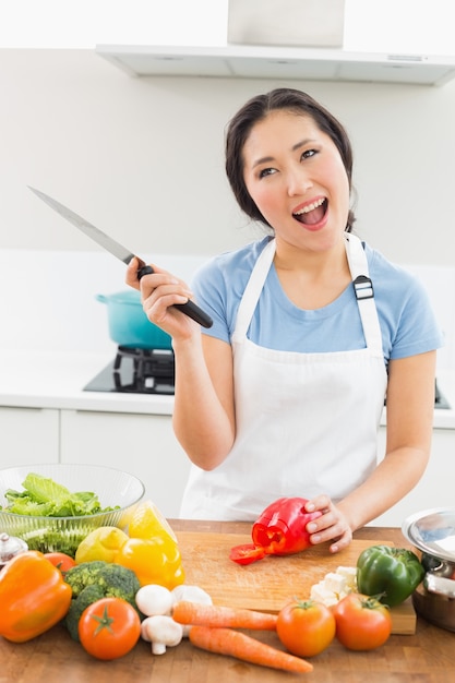 Femme souriante réfléchie, hacher les légumes dans la cuisine