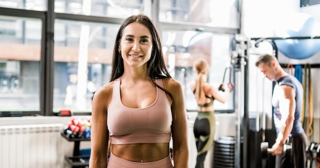 Femme souriante regardant la caméra pendant l'entraînement en salle de sport