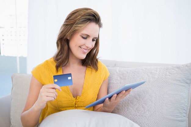 Femme souriante regardant son écran de la tablette