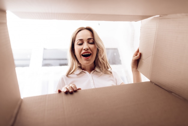 Femme souriante regarde dans une boîte vide de l&#39;intérieur.