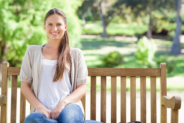 Femme souriante relaxante dans le parc sur un banc