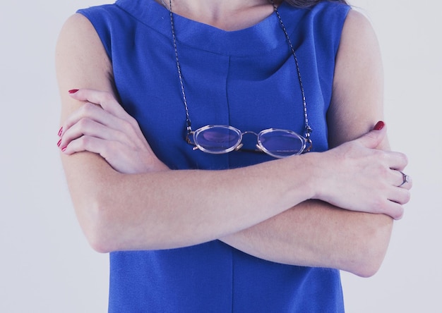 Femme souriante en robe avec les bras croisés sur fond blanc