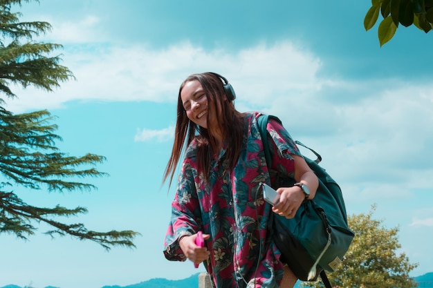 Une femme souriante avec un sac à dos debout contre le ciel