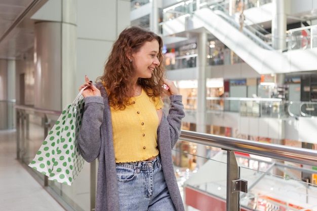 Femme souriante avec des sacs à provisions au centre commercial