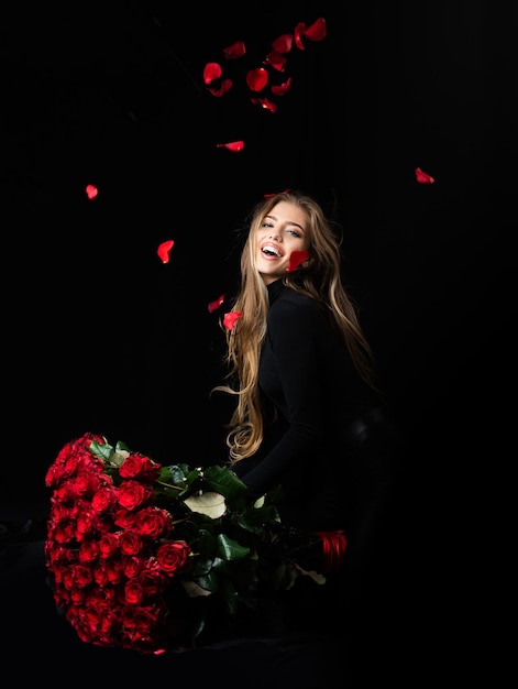 Femme souriante avec la Saint Valentin présente une fille sexy sensuelle avec un bouquet de roses