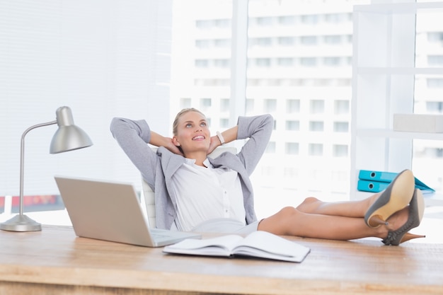 Femme souriante se détendre sur son bureau