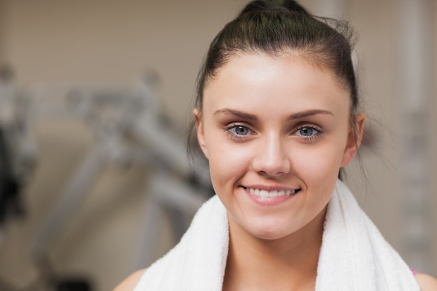 Femme souriante avec une serviette autour du cou dans une salle de sport
